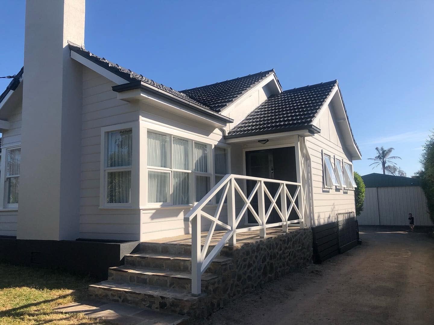 Tired 1950s weatherboard cottage brought back to life in a crisp coastal white with charcoal trim. — after