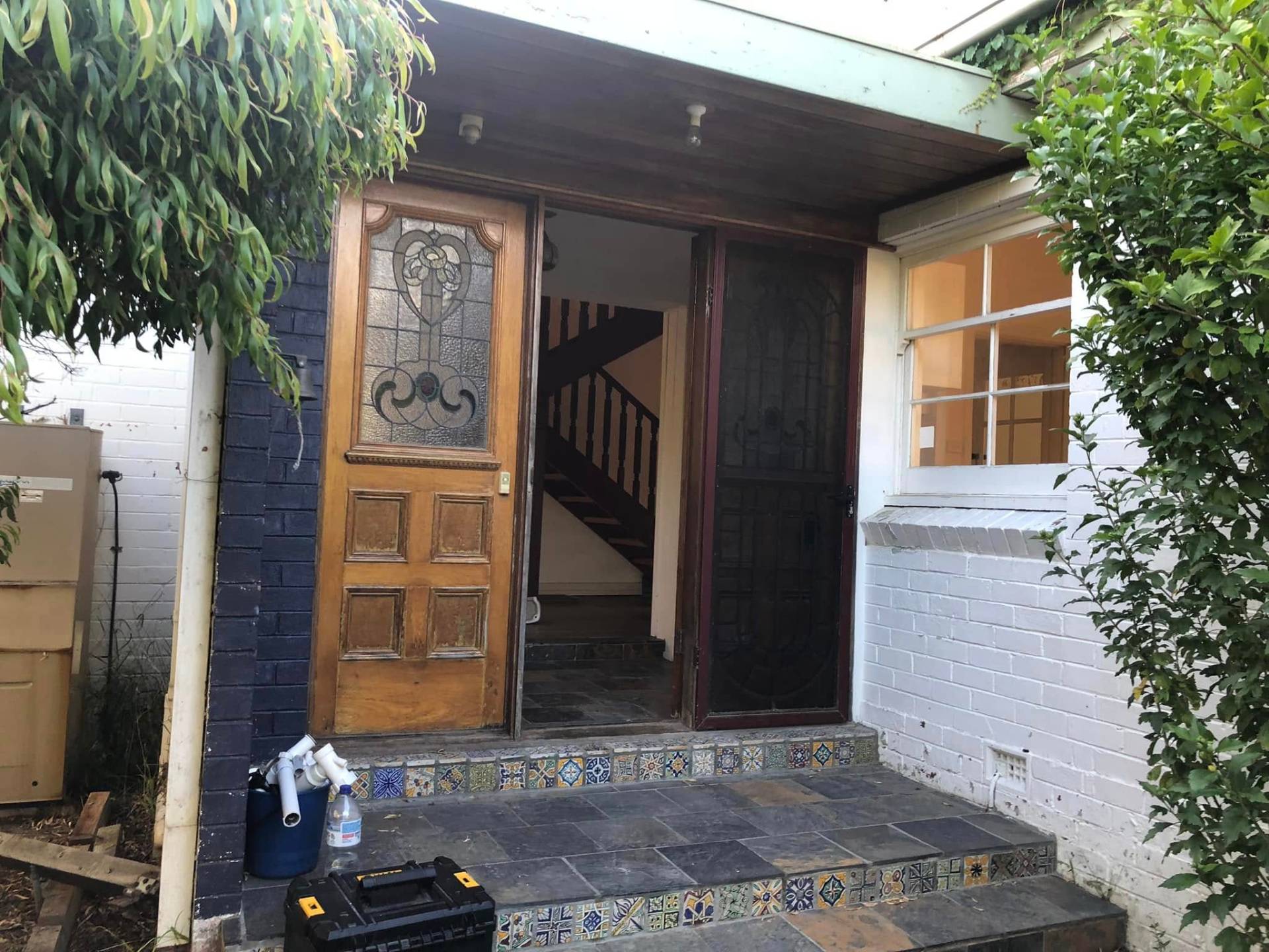 Weathered timber entry and dark brickwork transformed with a soft duck-egg door and clean white surrounds. — before